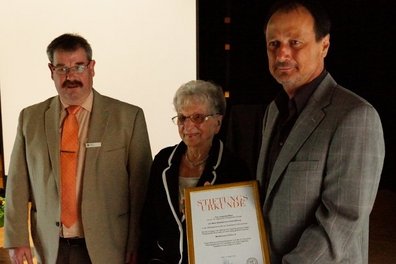 Lilo Meier umrahmt von Kurt Brunner (Sparkasse) und Robert Wagner (Schulleiter). Wagner zeigt Stiftungsurkunde in die Kamera.