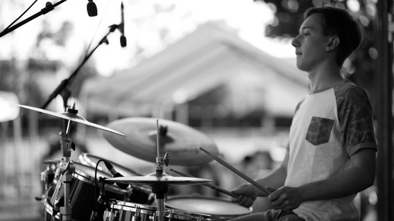 Junger Mann spielt Schlagzeug bei einem Open-Air-Konzert
