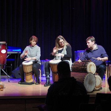 Erwachsene spielen auf verschiedenen afrikanischen Trommeln