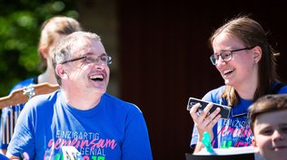Mann mit Behinderung und junge Frau lachen beim Musizieren