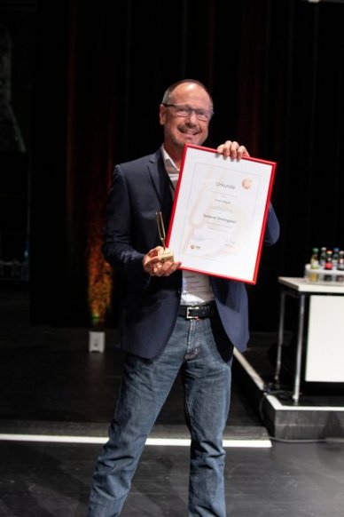 Robert Wagner mit der Goldenen Stimmgabel des VdM und der dazugehörenden Urkunde.