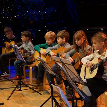 Gruppe von Kindern spielt gemeinsam Gitarre