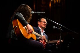 Gitarristin und Schulleiter Robert Wagner mit Gitarre auf der Bühne