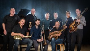 Gruppenbild Jazz-Combo mit Saxofon, Posaune, Trompete und Gitarre, im Hintergrund ein Flügel